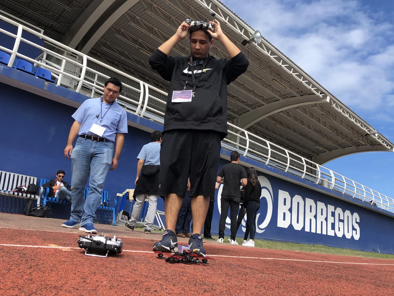 A participant adjusts his FPV goggles with a racing drone and radio controller on the track at LASIRS.
